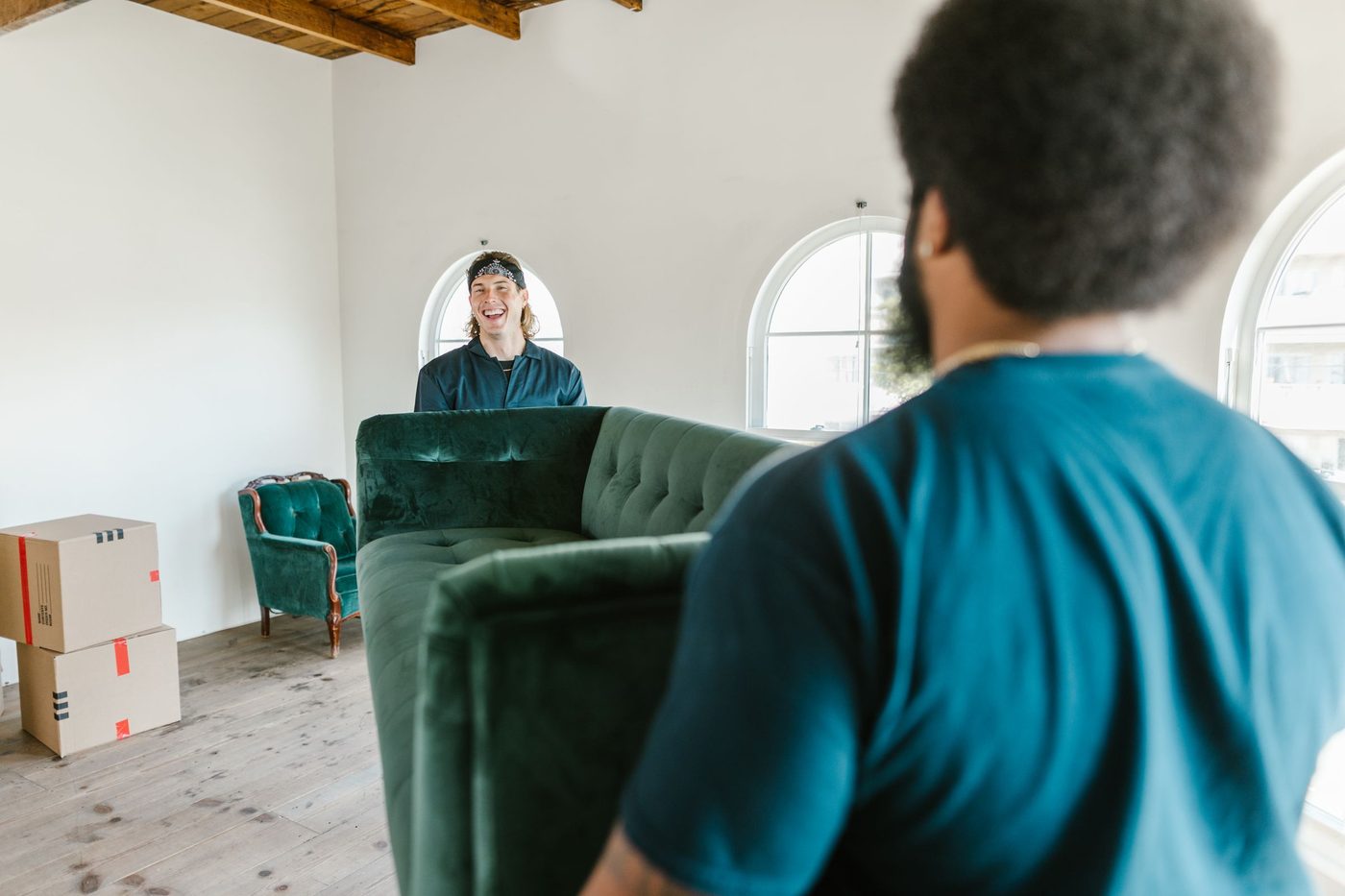 Two movers carrying a sofa into a bright new home